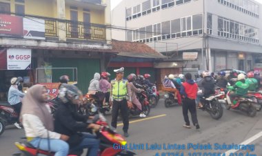 Ditengah Melaksanakan Gatur Lalin, Personil Polsek Sukalarang Bantu Seberangkan Karyawan